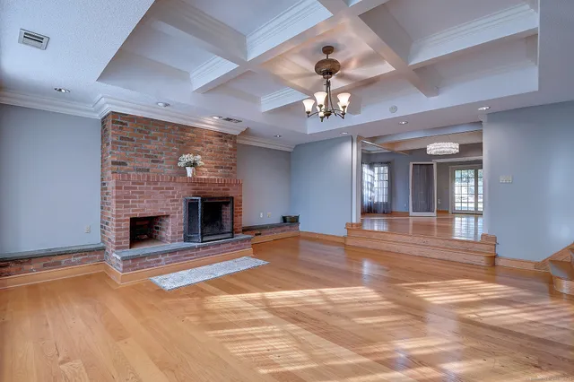 a view of an empty room with a fireplace and chandelier fan