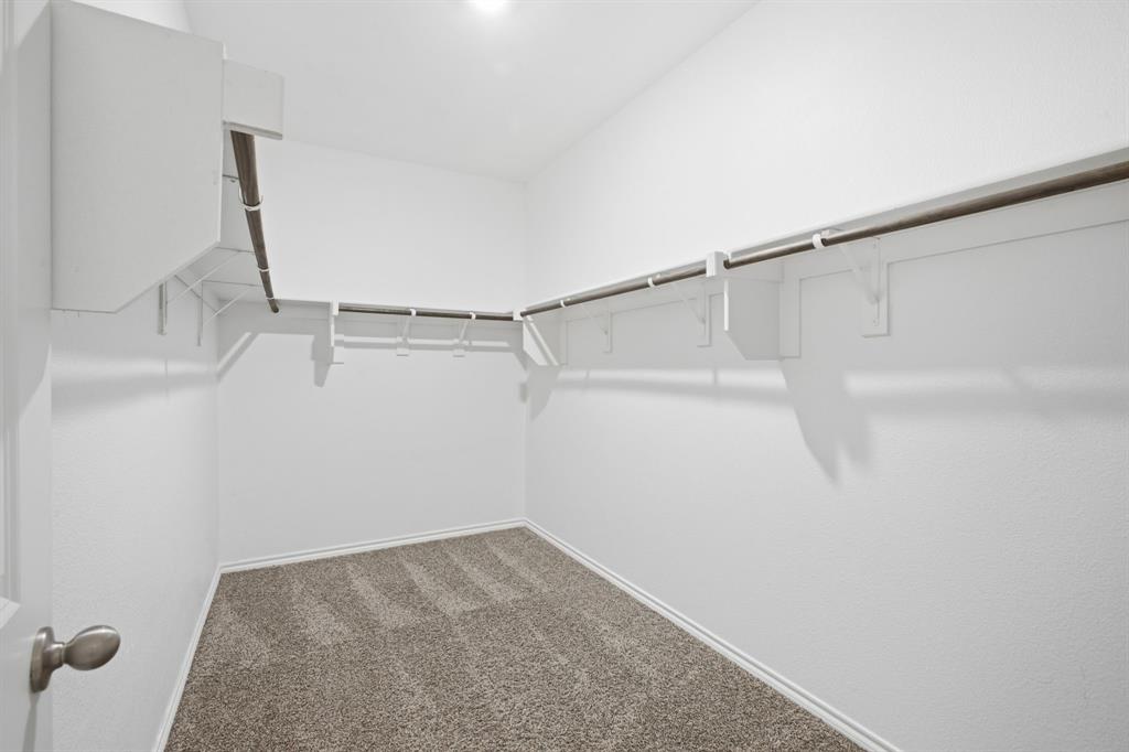 1328 Broaddus Road Forney, TX 75126 - Photo 20 of 31 Walk-in closet featuring white painted walls, a textured carpet floor, built-in shelving, and metal hanging rods