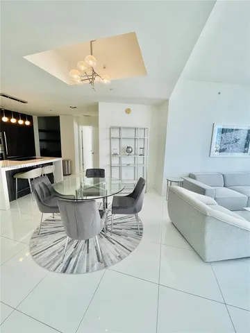 a living room with furniture a flat screen tv and kitchen view