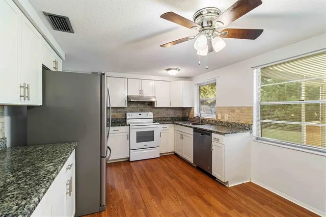 a kitchen with a refrigerator a stove cabinets and wooden floor