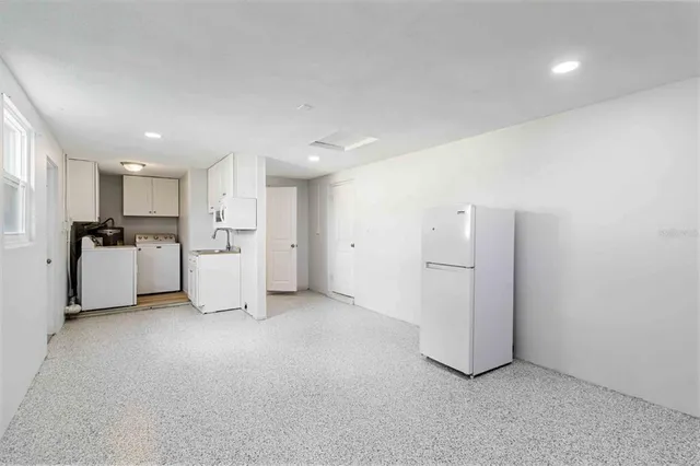 a view of a kitchen with refrigerator and white cabinets