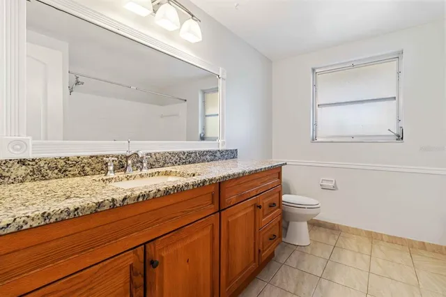 a bathroom with a granite countertop sink mirror vanity and toilet