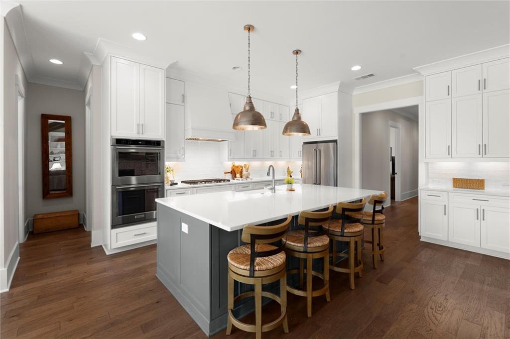 3809 Cochran Lake Road Marietta, GA 30062 - Photo 17 of 40 a kitchen with stainless steel appliances kitchen island granite countertop a wooden floor and white cabinets