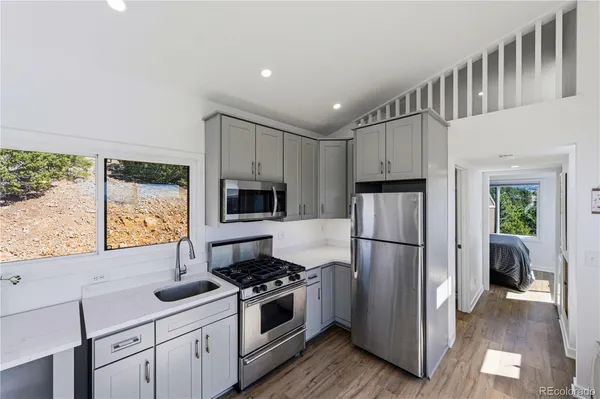 a kitchen with stainless steel appliances white cabinets and wooden floor