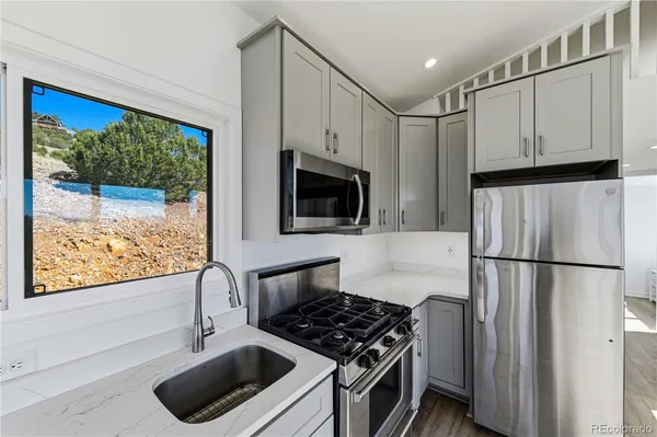 a kitchen with stainless steel appliances granite countertop a refrigerator a sink a stove and a refrigerator