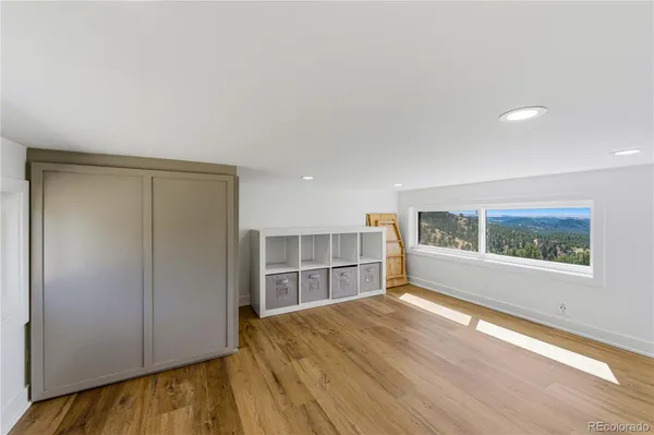a view of an empty room with a window and wooden floor