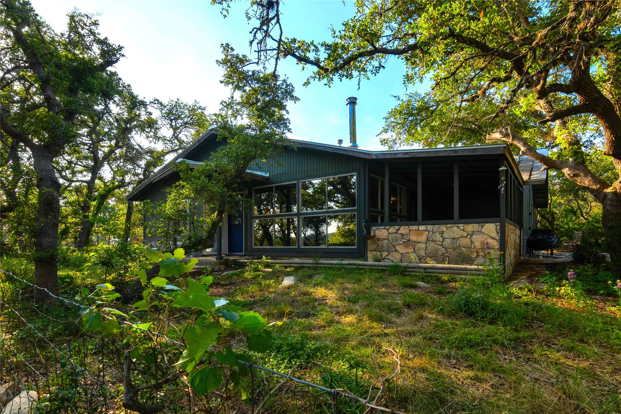 435 Spangenberg Road Blanco, TX 78606 - Photo 4 of 38 a view of a house with floor to ceiling window and a large tree