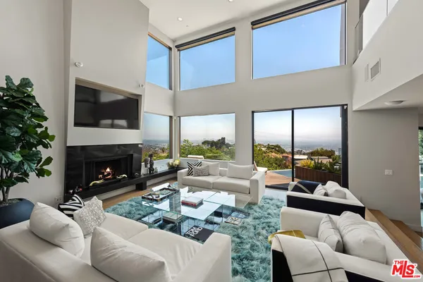 a living room with furniture a fireplace and a floor to ceiling window