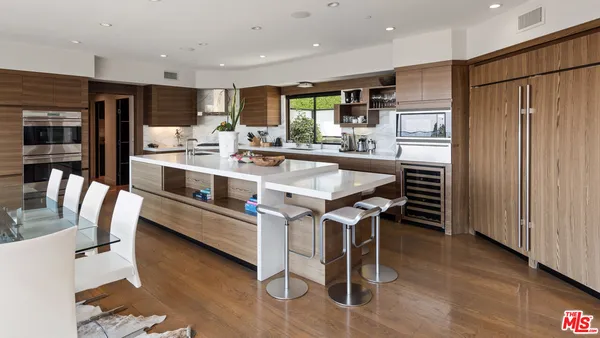 a kitchen with stainless steel appliances kitchen island granite countertop a table chairs refrigerator and microwave