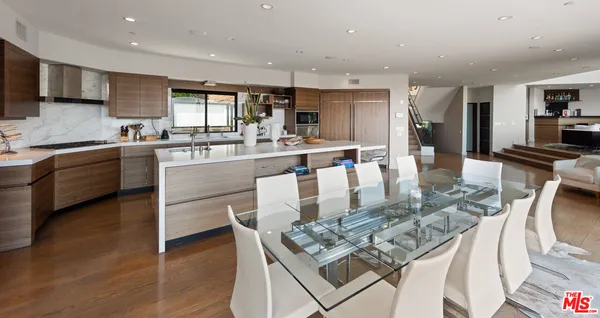 a kitchen with stainless steel appliances granite countertop a stove top oven a sink dishwasher and a dining table with wooden floor