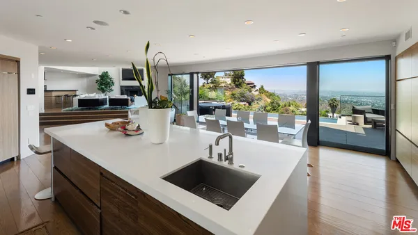 a kitchen with a sink a counter top space and living room view