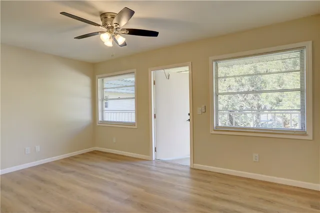 a view of an empty room with wooden floor and a window