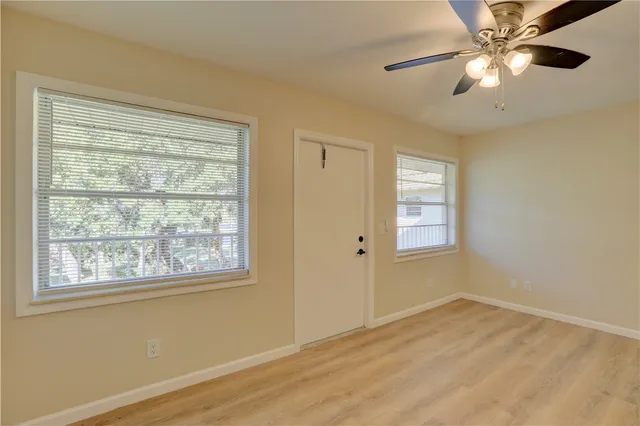a view of an empty room with a window and wooden floor