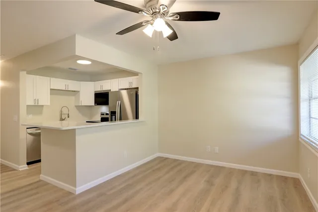 a kitchen with stainless steel appliances a microwave a stove and white cabinets with wooden floor