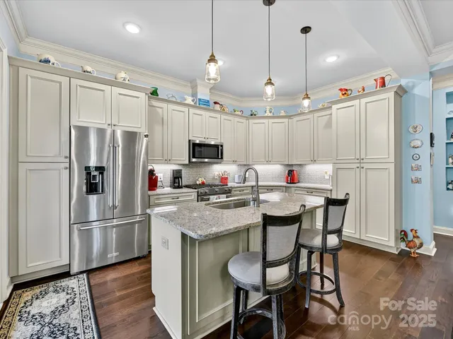 a kitchen with kitchen island granite countertop a table chairs stove and refrigerator