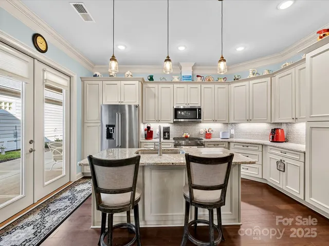 a kitchen with kitchen island a white cabinets and chairs