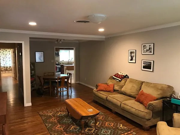 a living room with furniture and a dining table with wooden floor