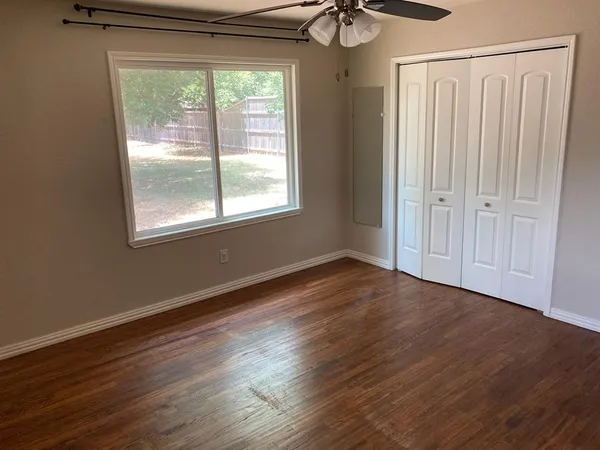 a view of an empty room with wooden floor and a window