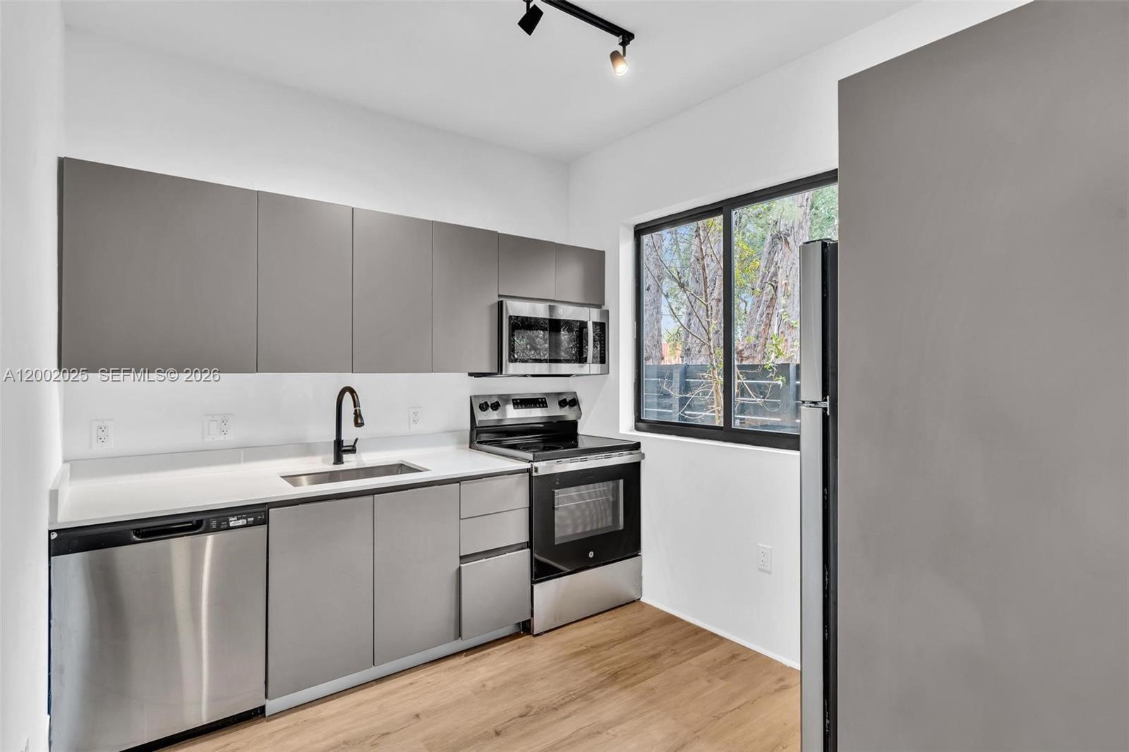 753 Northwest 30th Street, Unit 3 Miami, FL 33127 - Photo 2 of 35 a kitchen with stainless steel appliances granite countertop a sink stove and refrigerator