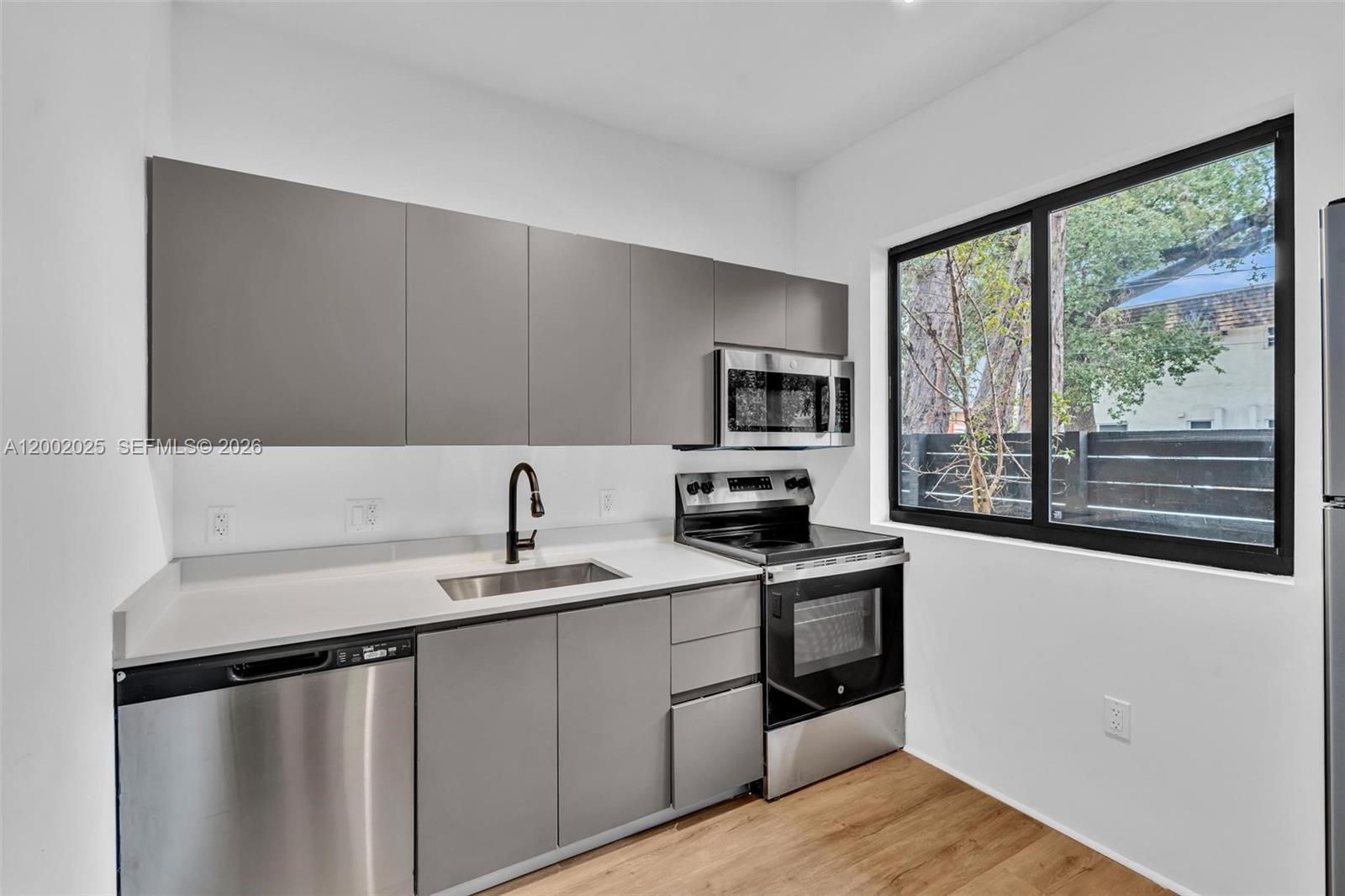 753 Northwest 30th Street, Unit 3 Miami, FL 33127 - Photo 3 of 35 a kitchen with stainless steel appliances a sink stove and cabinets