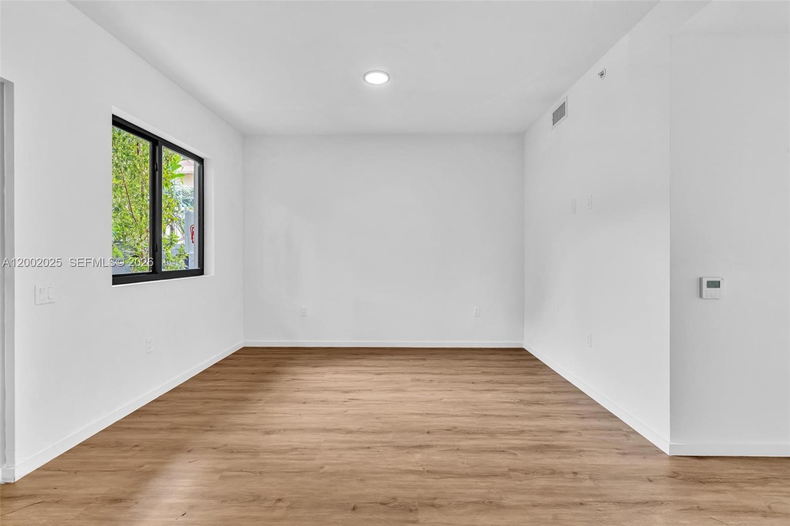 753 Northwest 30th Street, Unit 3 Miami, FL 33127 - Photo 6 of 35 a view of an empty room with wooden floor and a window