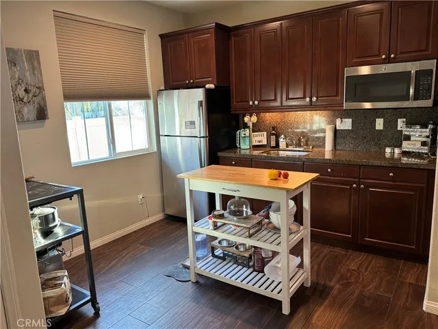 a kitchen with stainless steel appliances granite countertop a stove a refrigerator a sink and dishwasher with wooden floor