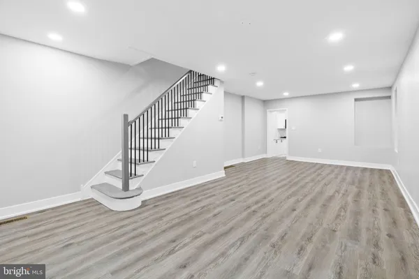 a view of an empty room with wooden floor and stairs