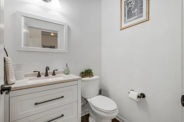 a bathroom with a toilet sink vanity and mirror