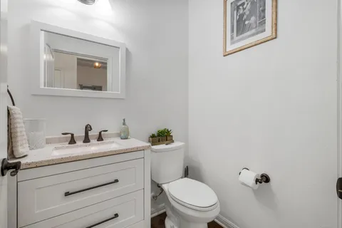 a bathroom with a toilet sink vanity and mirror