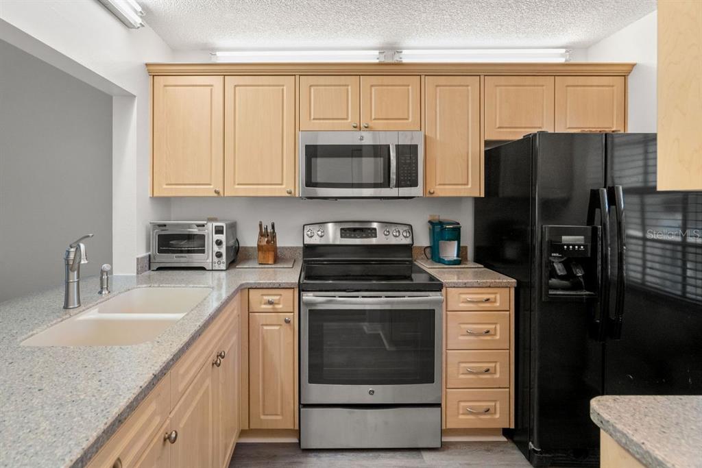 1438 Millstream Lane, Unit 203 Dunedin, FL 34698 - Photo 11 of 60 a kitchen with a stove microwave and refrigerator