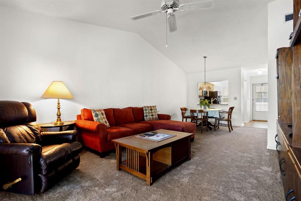 1438 Millstream Lane, Unit 203 Dunedin, FL 34698 - Photo 28 of 60 a living room with furniture a lamp and a chandelier