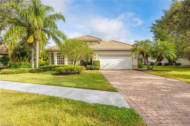 a front view of a house with a yard and palm trees
