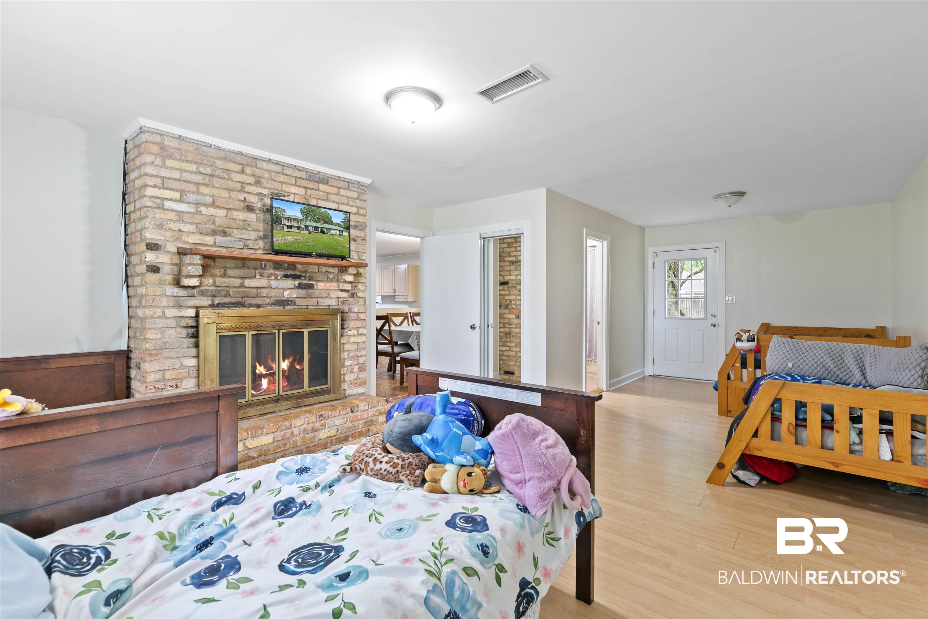 10420 Johnson Road South Mobile, AL 36695 - Photo 27 of 75 Spacious room featuring a brick fireplace with a brass-trimmed firebox, wood mantel, and wood-finish flooring