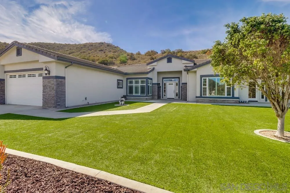 a front view of a house with a yard and palm trees