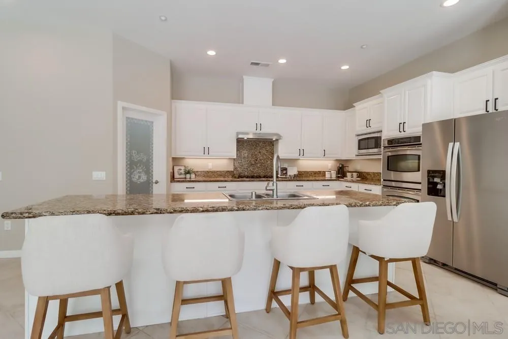 8837 Diamondback Drive Santee, CA 92071 - Photo 11 of 37 a kitchen with kitchen island granite countertop a sink and white cabinets