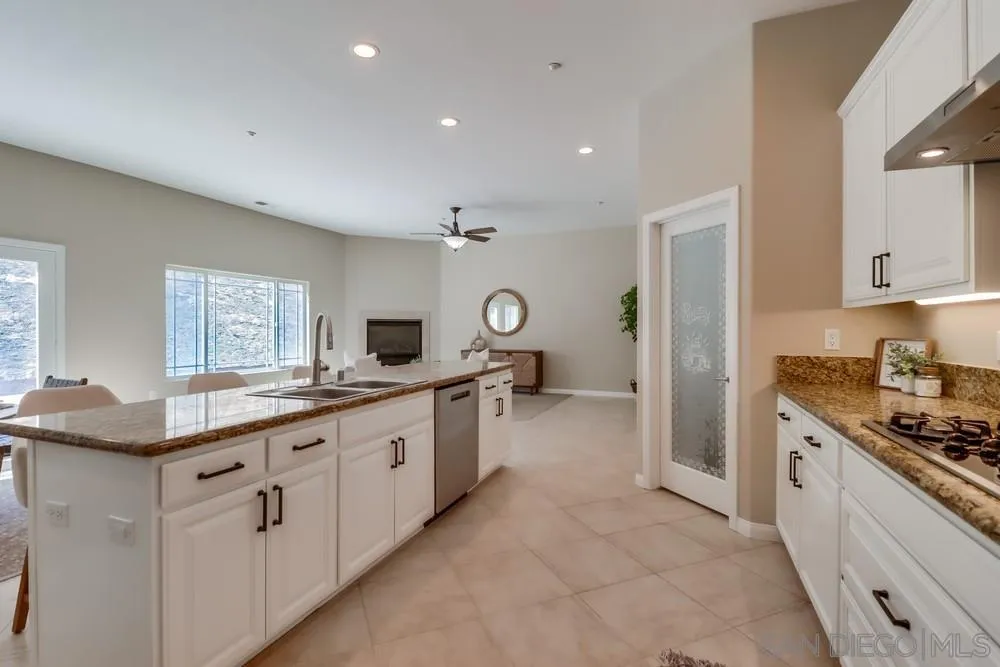 8837 Diamondback Drive Santee, CA 92071 - Photo 8 of 37 a large white kitchen with granite countertop a sink and dishwasher a stove with wooden cabinets