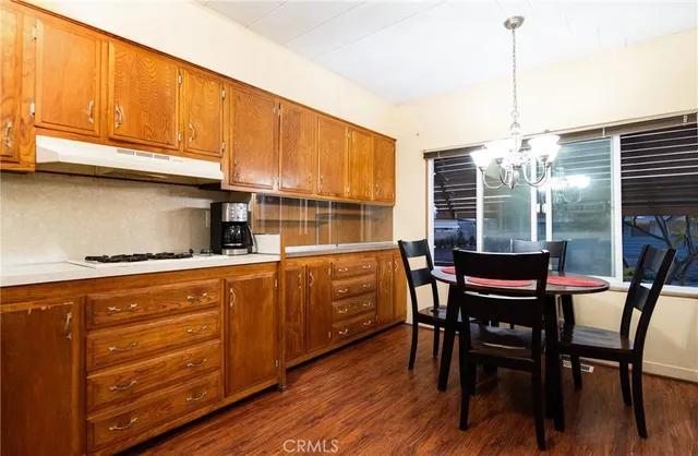 a kitchen with stainless steel appliances kitchen island granite countertop a table chairs and wooden cabinets