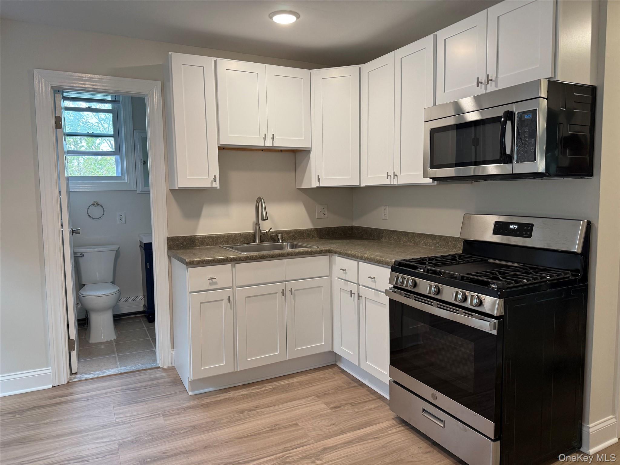 Kitchen featuring gas range, white cabinetry, and light wood-style flooring