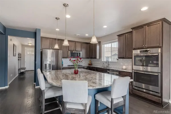 a kitchen with stainless steel appliances kitchen island granite countertop a kitchen island and chairs in it