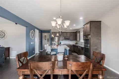 a dining room with furniture a kitchen and chandelier