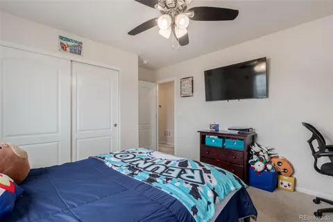 a bedroom with a bed a flat tv screen and a dresser