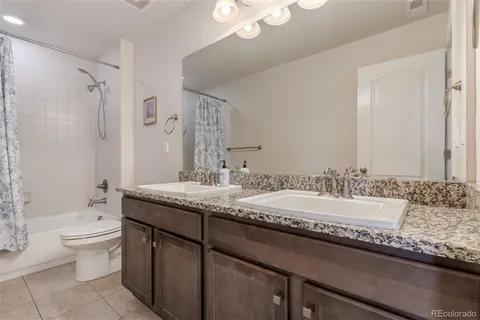 a bathroom with a granite countertop double vanity sink a mirror and a bathtub