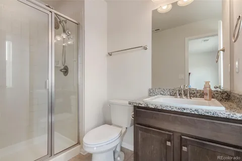 a bathroom with a granite countertop sink toilet and shower