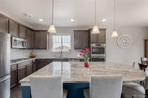 a kitchen with stainless steel appliances granite countertop a sink a stove and a refrigerator