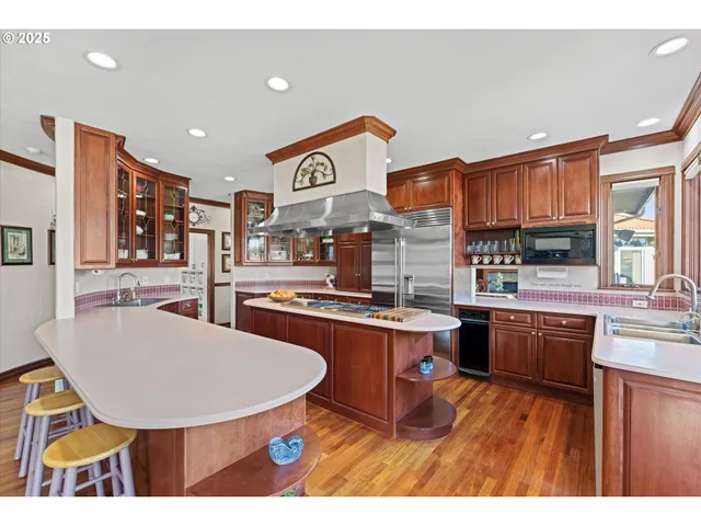 a kitchen with stainless steel appliances granite countertop a sink a stove a dining table and chairs