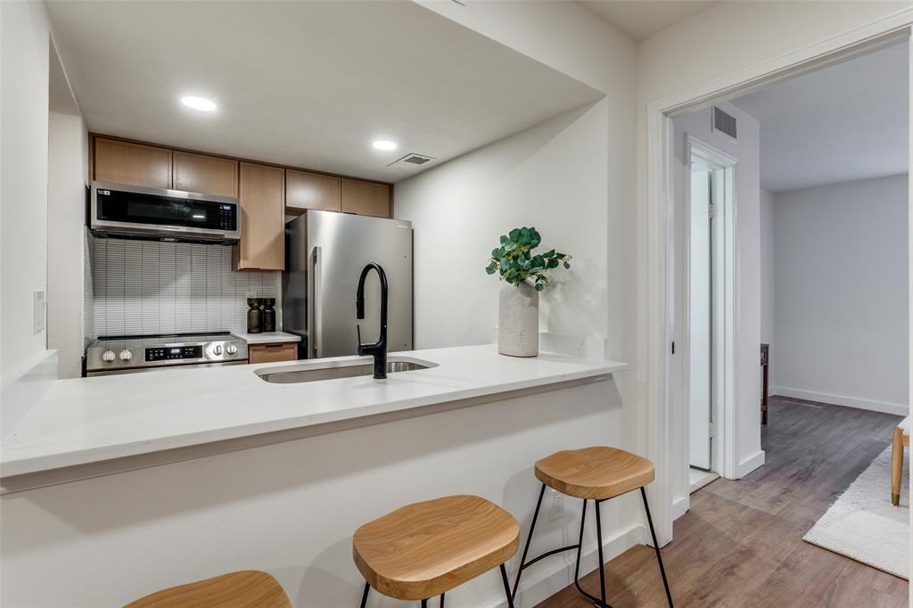4525 Gilbert Avenue, Unit 202 Dallas, TX 75219 - Photo 6 of 13 a kitchen with stainless steel appliances a dining table chairs and wooden floor