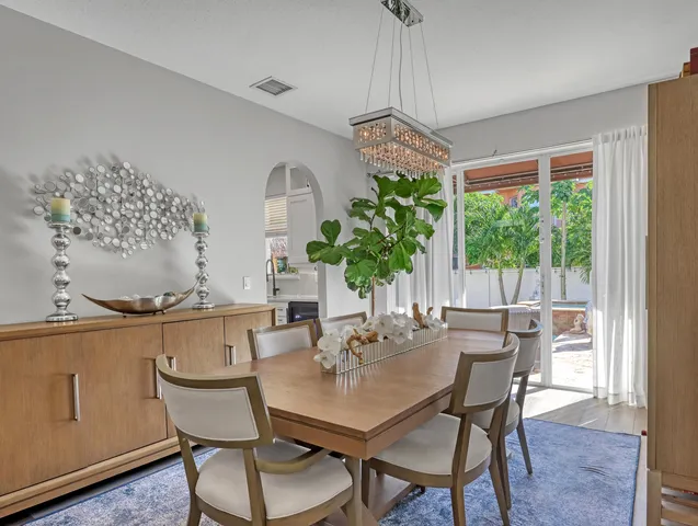 a kitchen with stainless steel appliances kitchen island a table chairs in it and white cabinets