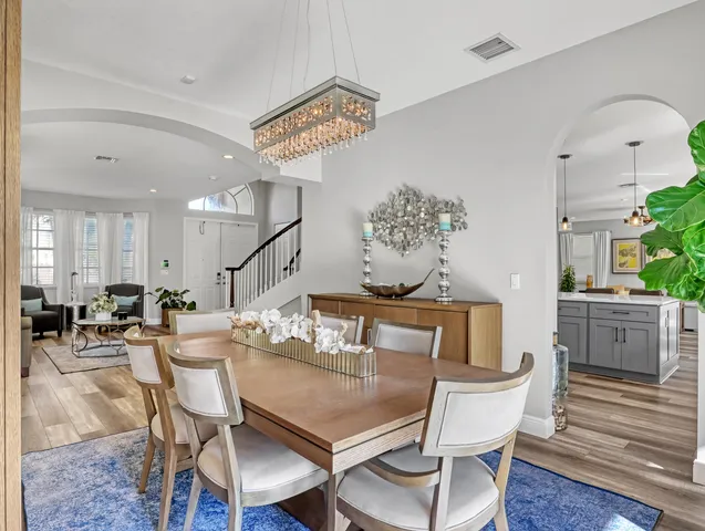 a kitchen with stainless steel appliances granite countertop a refrigerator a stove and a dining table with wooden floor