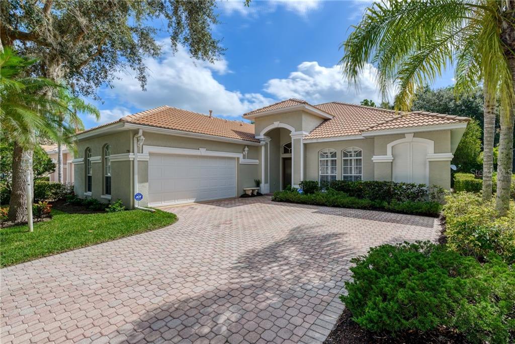 7750 US Open Loop Lakewood Ranch, FL 34202 - Photo 1 of 1 a view of a white house next to a yard with palm trees