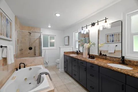 a bathroom with a granite countertop tub sink double vanity granite and shower